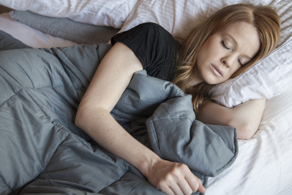 Woman sleeping while using a weighted blanket