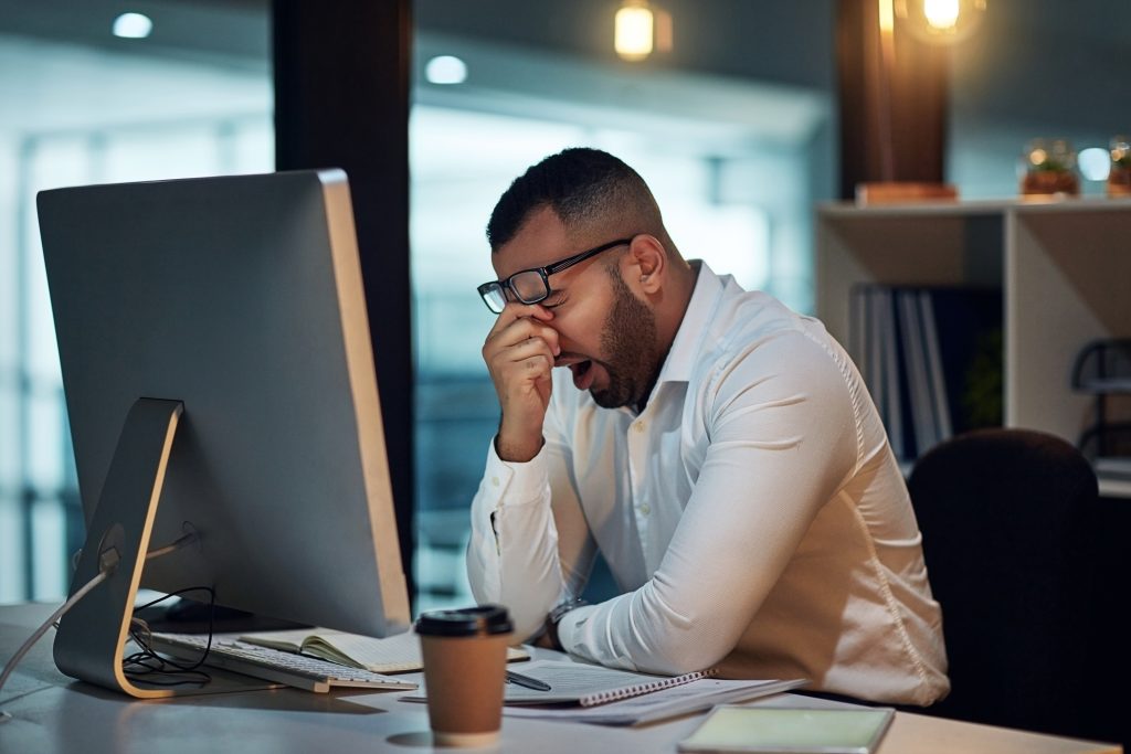 Office worker visibly tired at his computer desk