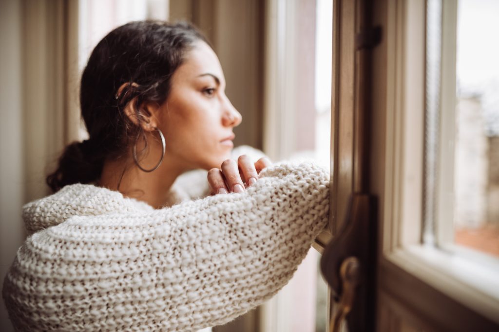 Female looking out of window, deep in thought.
